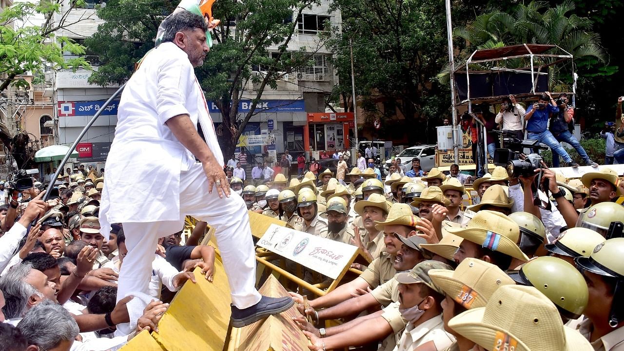 KPCC President D K Shivakumar climbs a barricade during a protest rally demanding the removal of KS Eshwarappa from the Karnataka Government in Bengaluru. Credit: IANS Photo