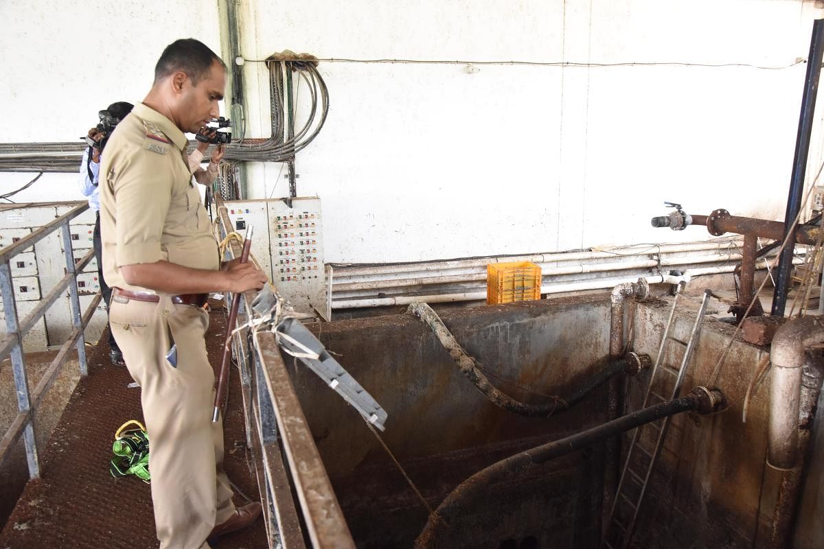 A policeman inspects the fish waste tank of Ulka LLP, situated in Mangaluru Special Economic Zone jurisdiction, on the outskirts of Mangaluru. DH Photo