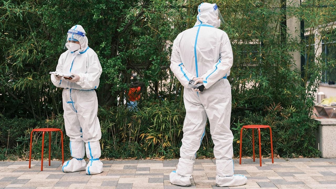 Community volunteers wearing personal protective equipment stand during a test for the Covid-19 coronavirus in a compound during a Covid-19 lockdown in Pudong district in Shanghai. Credit: AFP photo