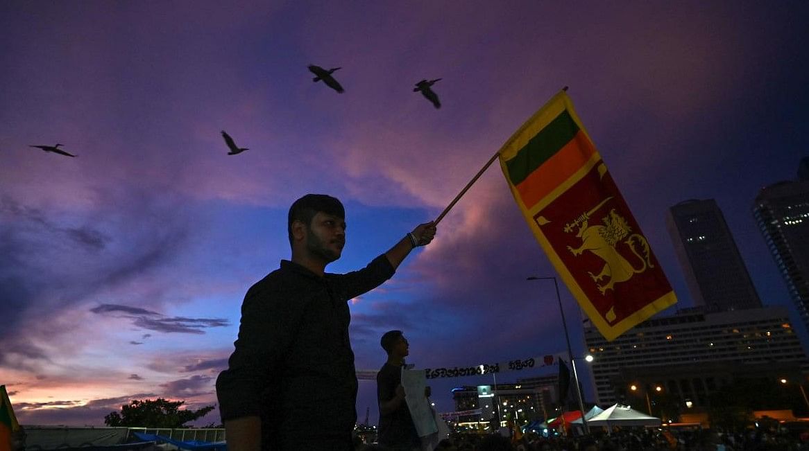 A protester hold a Sri Lanka's national flag as he participates along with others in an anti-government demonstration in Colombo. Credit: AFP