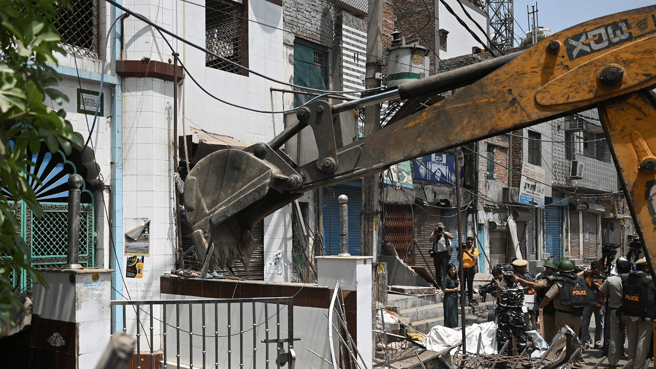 A bulldozer demolishes an illegal structure next to a mosque in a residential area of Jahangirpuri. Credit: AFP Photo
