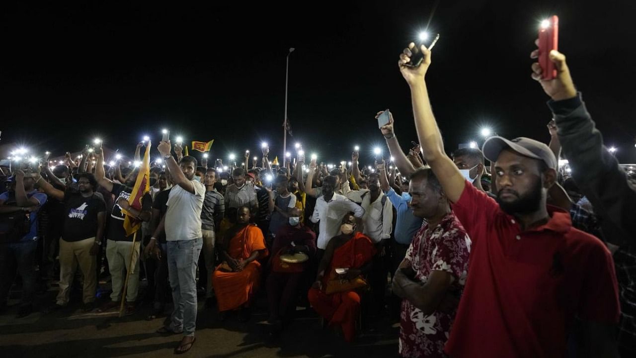 Sri Lankans hold up their mobile phone torches during a vigil condemning police shooting at protesters in Rambukkana. Credit: AP/PTI Photo