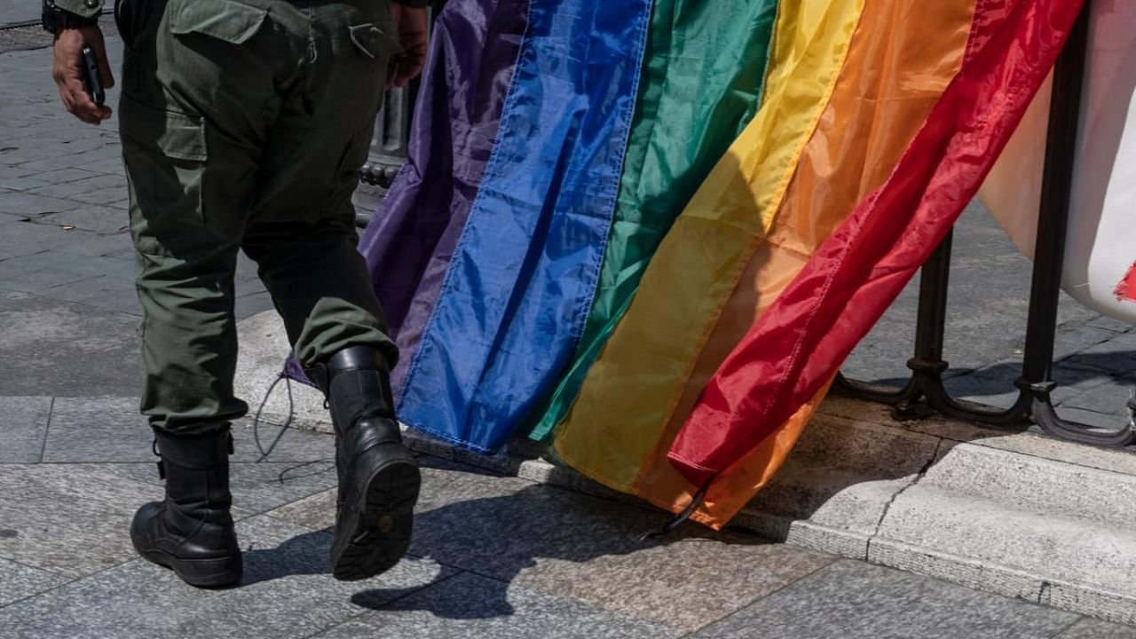 A member of the Bolivarian National Guard wearing his uniform walks in front of rainbow flags placed by members of the LGBTI community promoting an event in Caracas, on February 22, 2022. Credit: AFP Photo