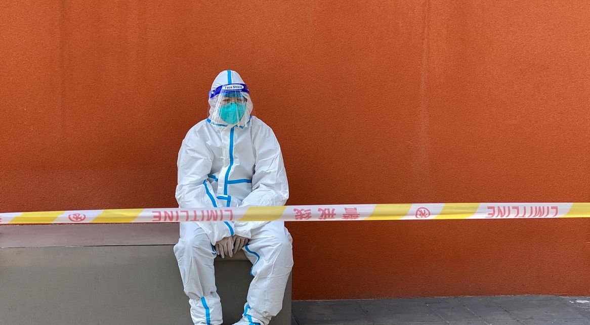 A worker in a protective suit sits near a police line outside a store, following the coronavirus disease (COVID-19) outbreak in Shanghai, China April 21, 2022. REUTERS/Andrew Galbraith