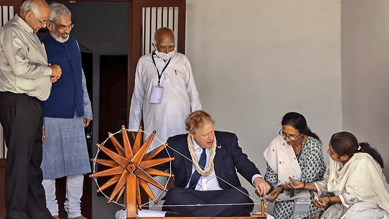 United Kingdom Prime Minister Boris Johnson tries his hands on a spinning wheel as Gujarat Chief Minister Bhupendra Patel looks on. Credit: PTI Photo