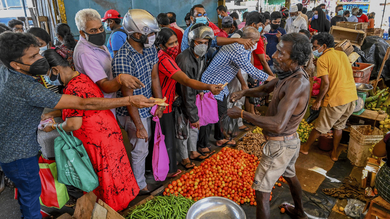 People buy vegetables at a market in Colombo. Credit: AFP Photo