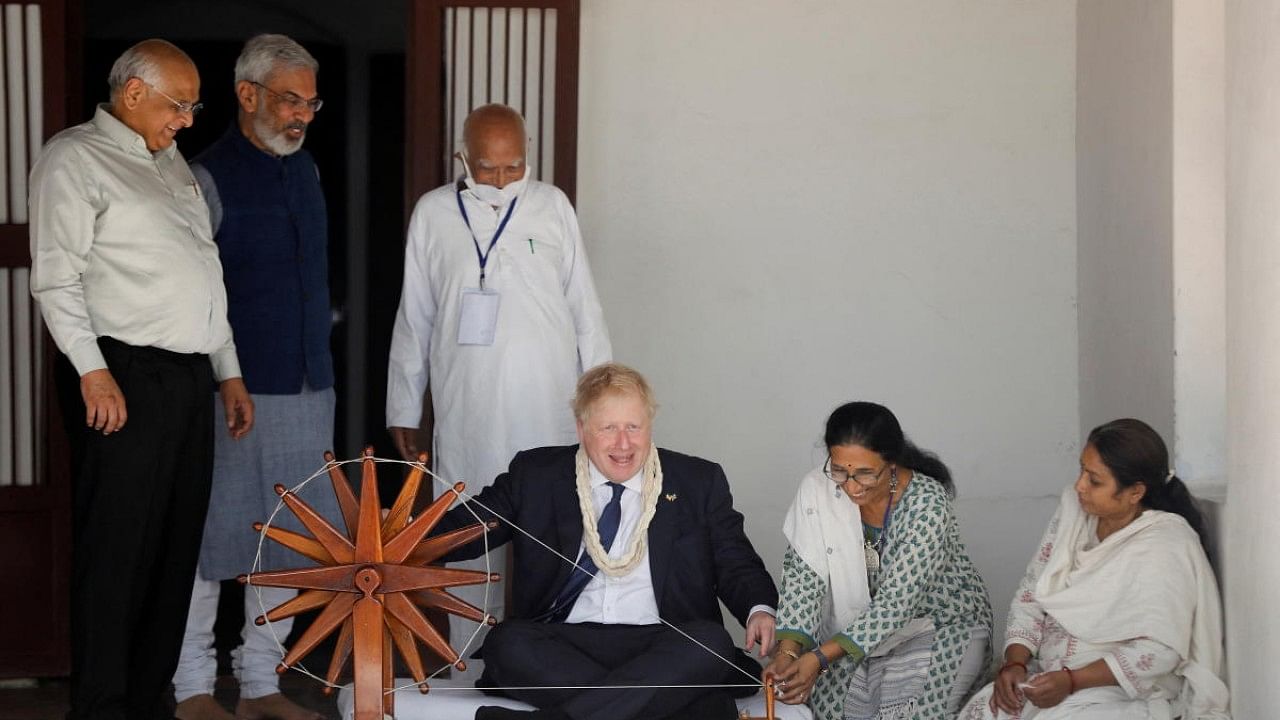 Britain's PM Boris Johnson spins cotton on a wheel during his visit to Gandhi Ashram in Ahmedabad. Credit: Reuters Photo