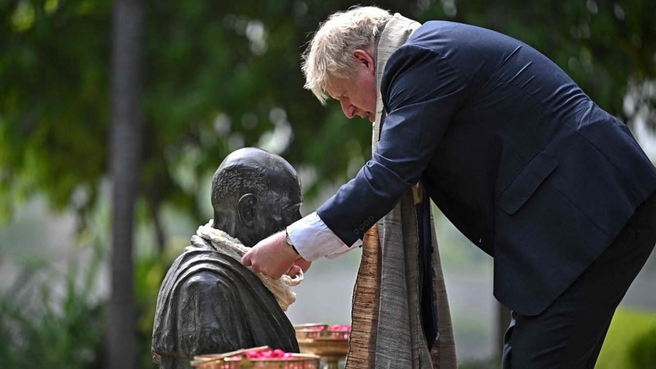 Britain's Prime Minister Boris Johnson places a garland on the statue of Mahatma Gandhi during his visit at the Sabarmati Ashram. Credit: AFP Photo