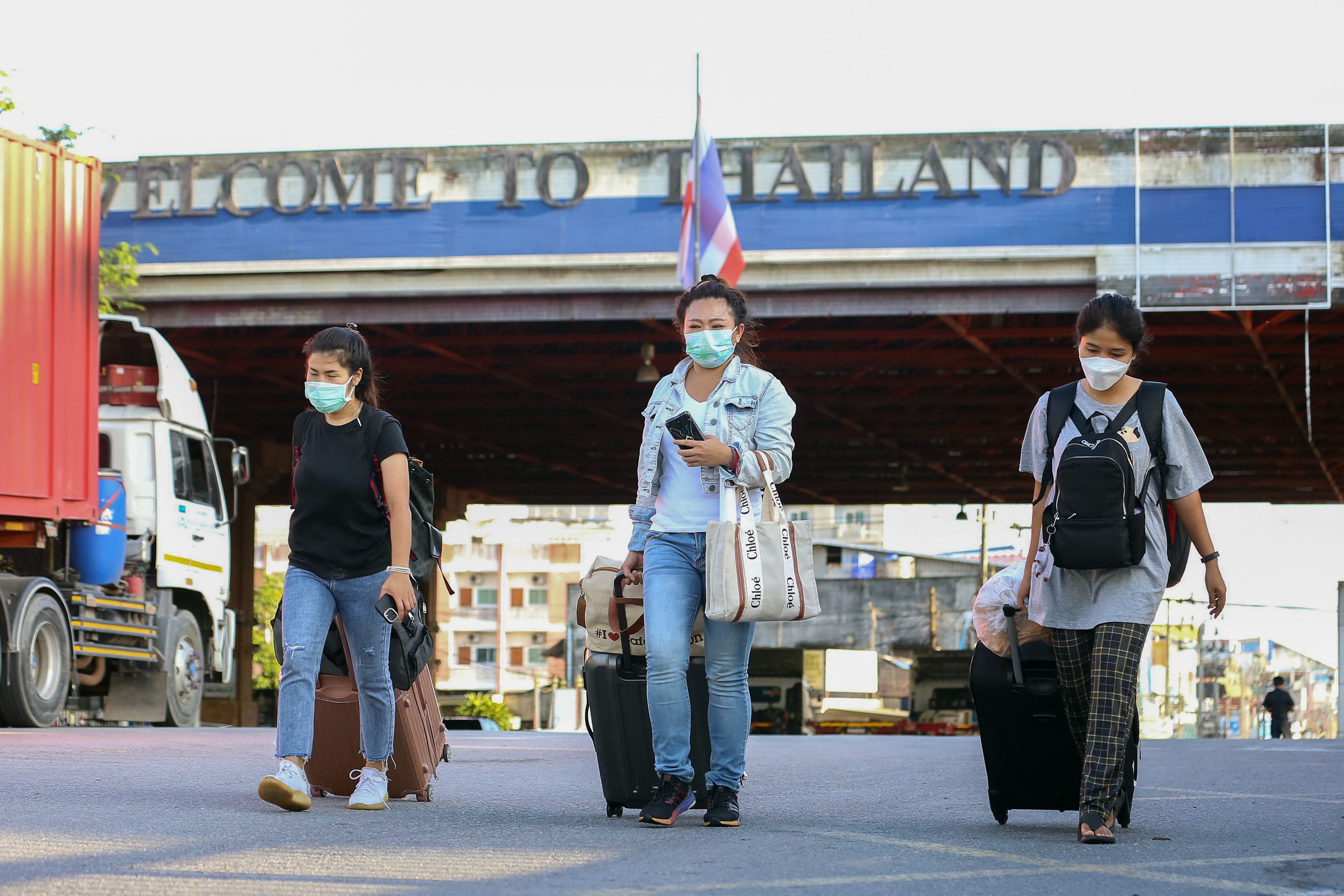 Thai women walk with luggage by the Sadao border checkpoint to travel into Malaysia from Thailand's southern Songkhla province. Credit: AFP Photo