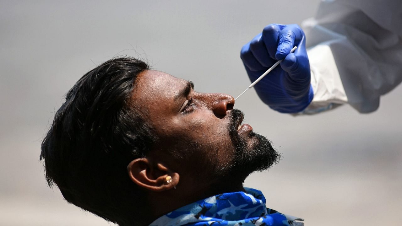 A healthcare worker collects swab samples from people for coronavirus at Majestic bus stand, Bengaluru. Credit: DH Photo