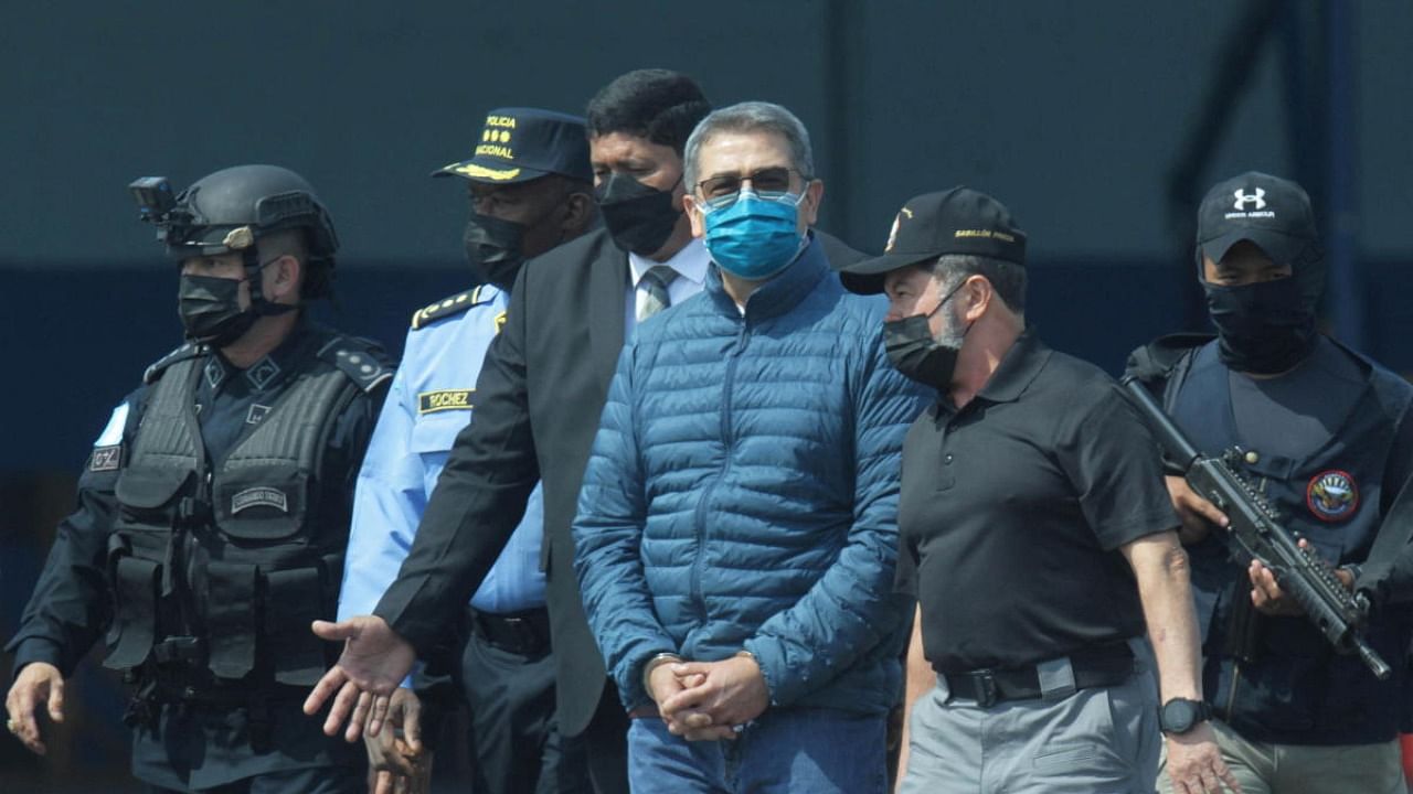 Honduras former President Juan Orlando Hernandez is escorted by authorities as he walks towards a plane of the US Drug Enforcement Administration (DEA) for his extradition to the United States. Credit: Reuters photo