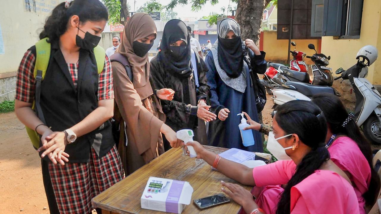 Students sanitise their hands and undergo thermal testing before appearing for the Karnataka 2nd PUC (Pre-University Certificate) Board exams, in Chikmagalur. Credit: PTI Photo