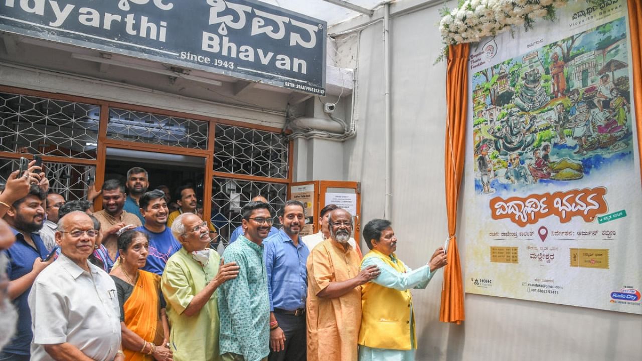 T S Nagabharana, Chairman, Kannada Development Authority unveil Vidyarthi Bhavan on stage poster in front of Vidyarthi Bhavan. Credit: DH Photo