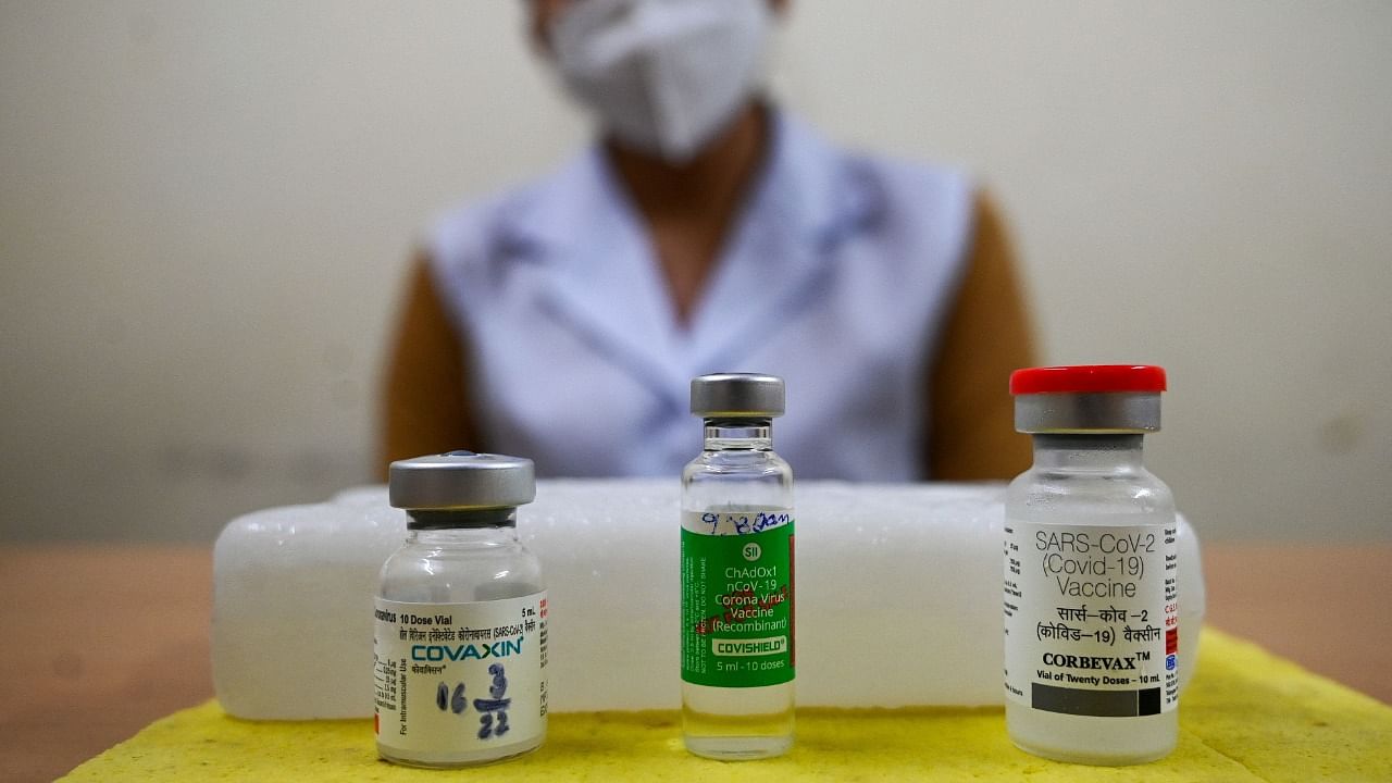 A health worker shows vials of Corbevax (R), Covishield (C) and Covaxin vaccines. Credit: AFP Photo