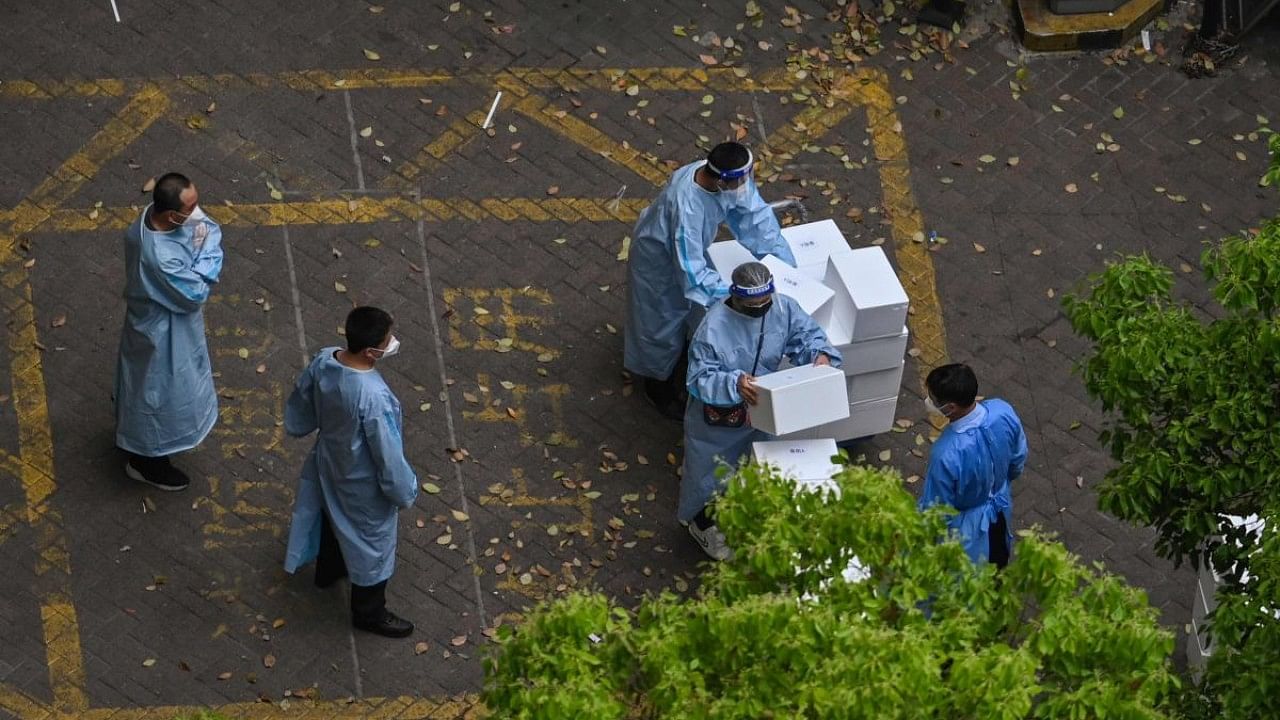 Workers wearing protective gear stack boxes during a Covid-19 coronavirus lockdown in the Jing'an district in Shanghai. Credit: AFP Photo