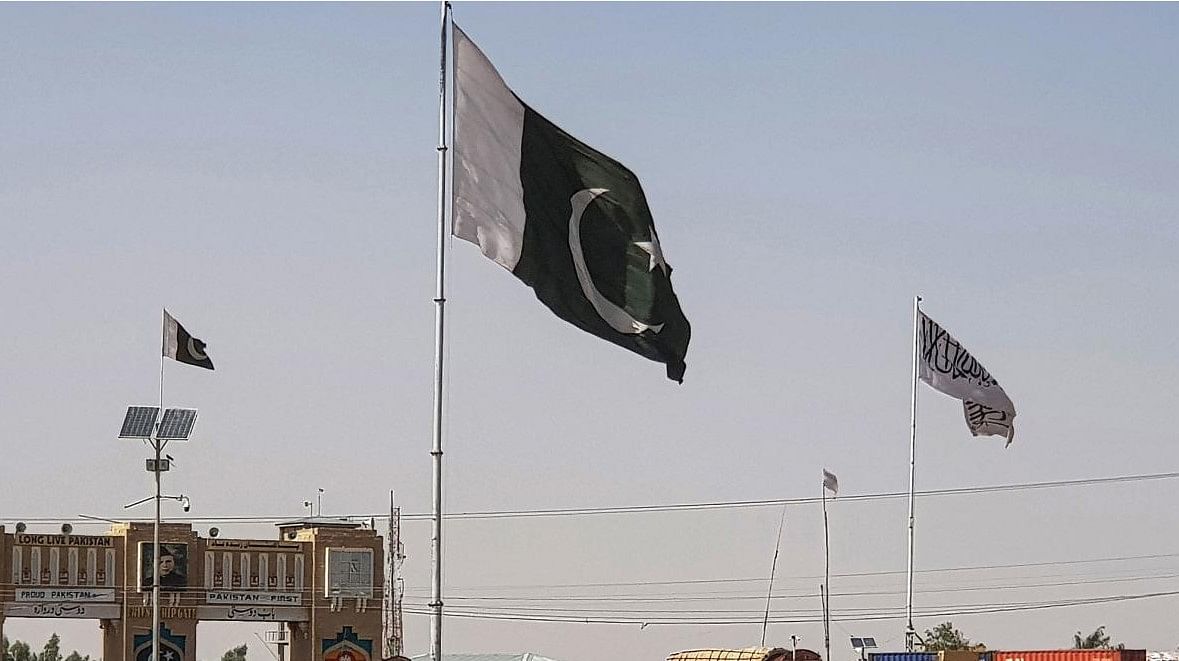 Pakistani flags (C) and Taliban flag (R) flutter on their respective border sides as seen from the Pakistan-Afghanistan border crossing point in Chaman. Credit: AFP