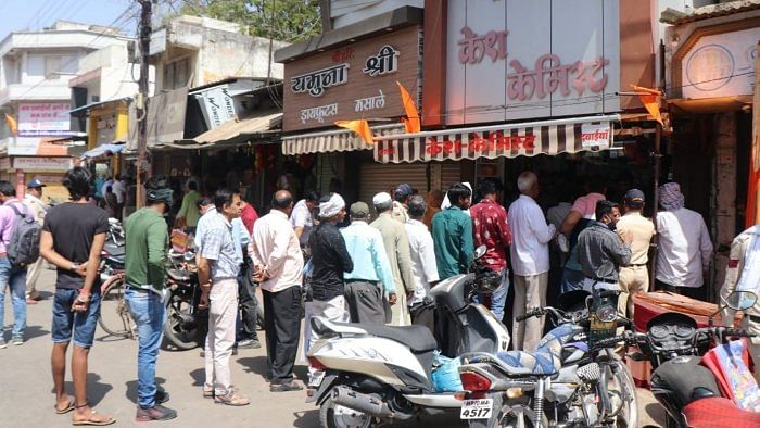 Locals queue up to buy medicines as the curfew is relaxed in Khargone. Credit: IANS Photo