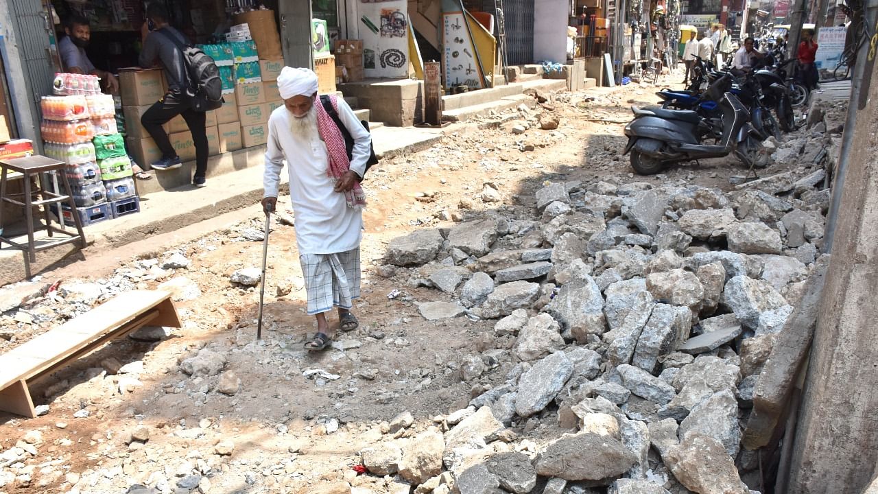 An elderly man struggles to walk after BBMP dug up SJP road in Bengaluru. Credit: DH Photo/B K Janardhan