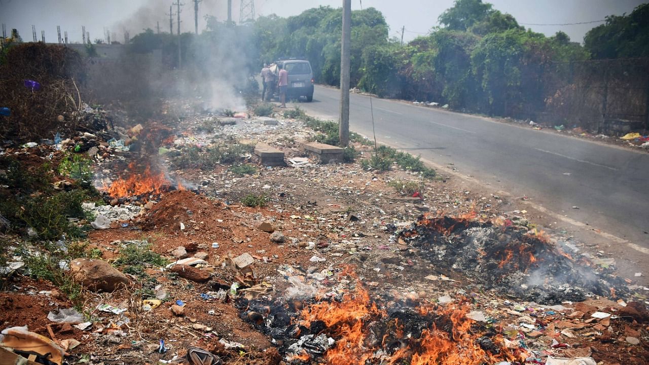 Garbage set on fire in an empty site at Subramanyapura. Rules prohibit burning of waste in buildings, on the roadside or in vacant sites. Credit: DH File Photo