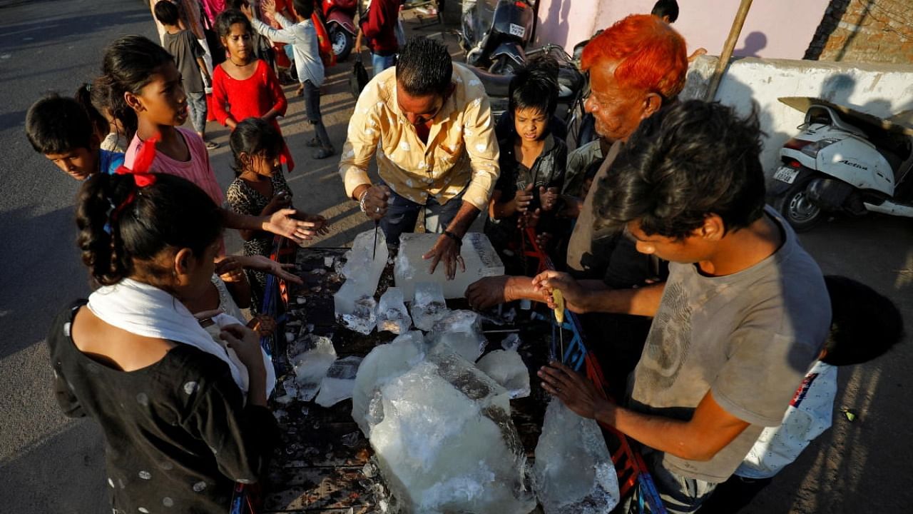 A man breaks a block of ice to distribute it among the residents of a slum during hot weather in Ahmedabad. Credit: Reuters photo