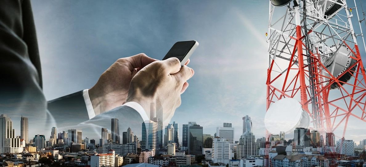 [Representational Image] Businessman using smartphone with cityscape, and telecommunication towers. Credit: Getty Images