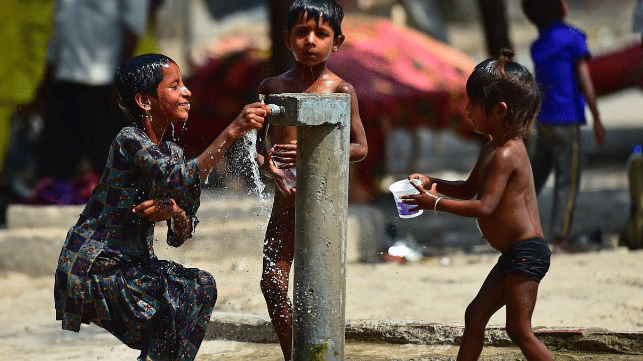Children take a bath from a roadside tap on a hot summer day. Credit: AFP Photo