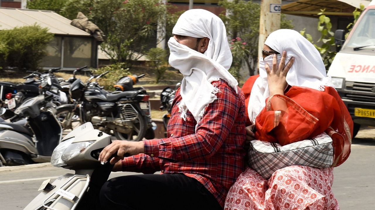 Motorists cover their faces with cloth while travelling on a hot summer day in Amritsar. Credit: AFP Photo
