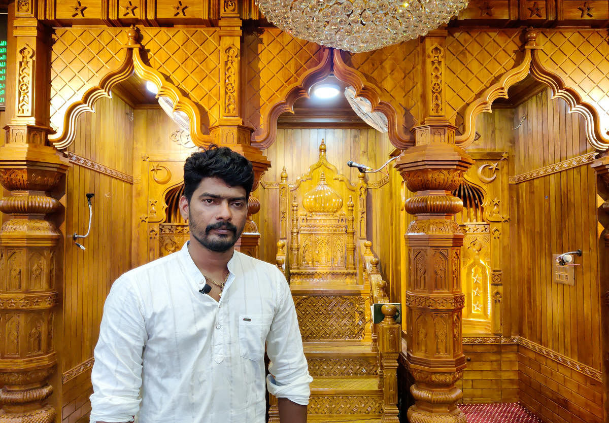 Harish Acharya in the backdrop of wooden carvings at Badriya Jumma Masjid in Pakshikere. DH Photo/Irshad Mahammad
