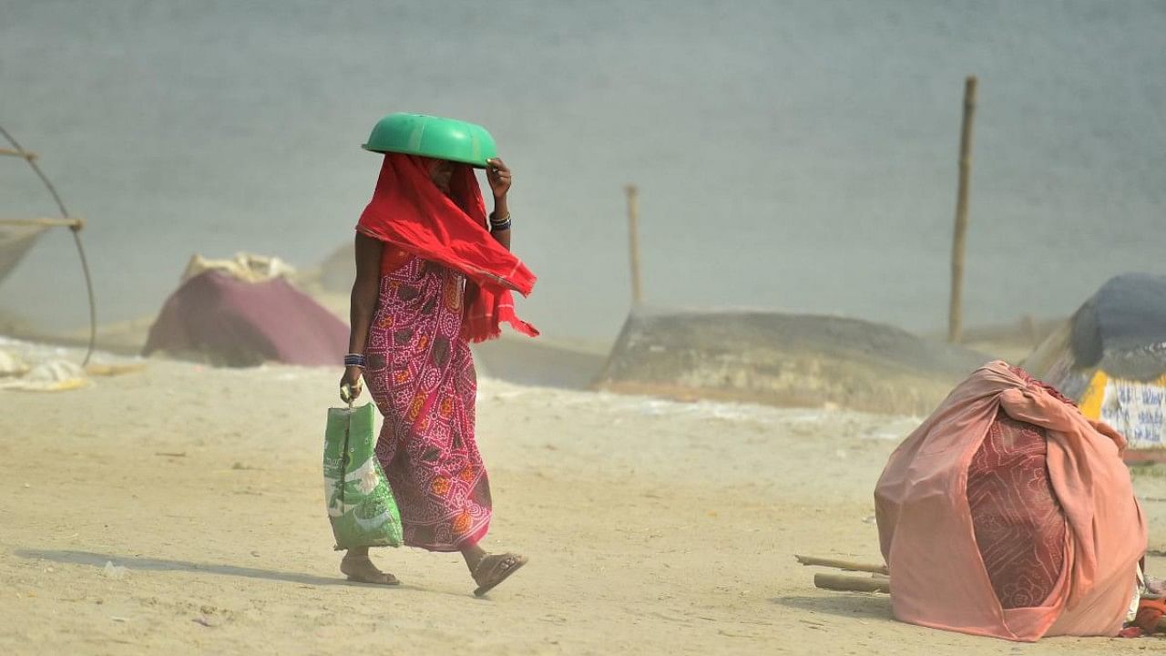 A woman covers her head with a plastic tub as she walks near Sangam, the confluence of the rivers Ganges, Yamuna and mythical Saraswati, on a summer afternoon in Allahabad. Credit: AFP Photo