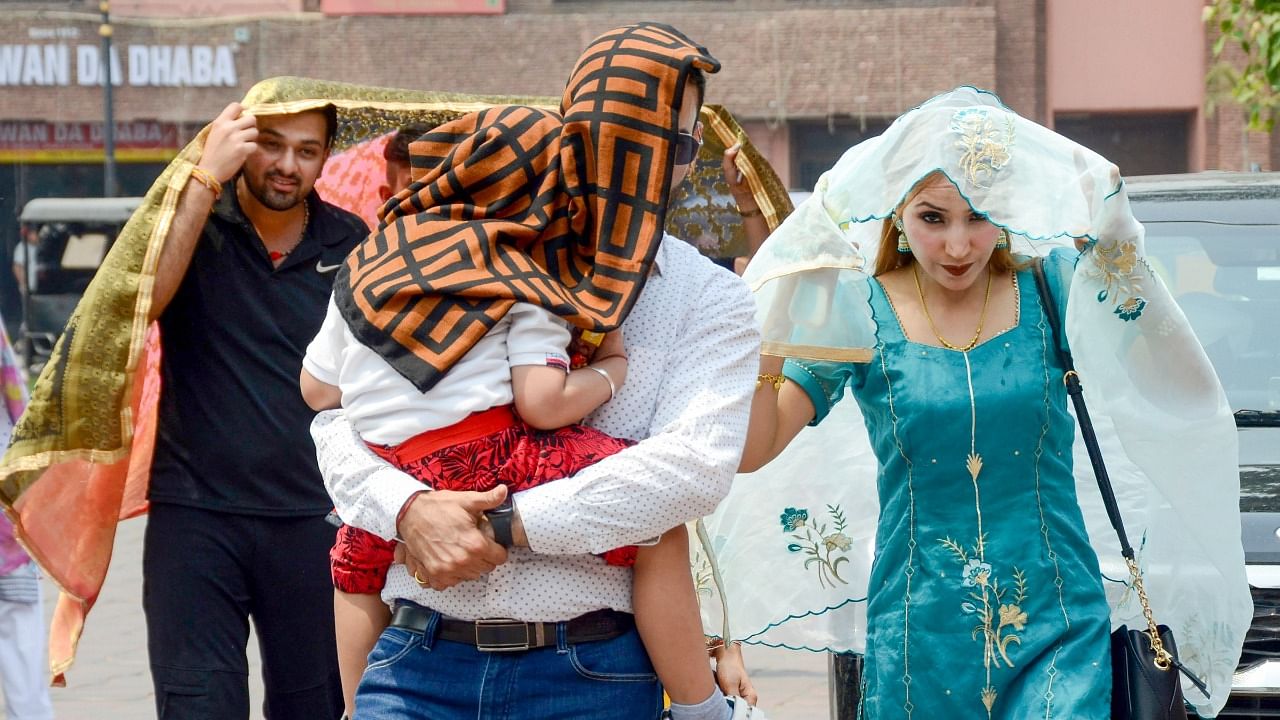  Commuters cover themselves with pieces of cloth to shield themselves from the sun, on a hot summer day, near Golden Temple in Amritsar. Credit: PTI Photo