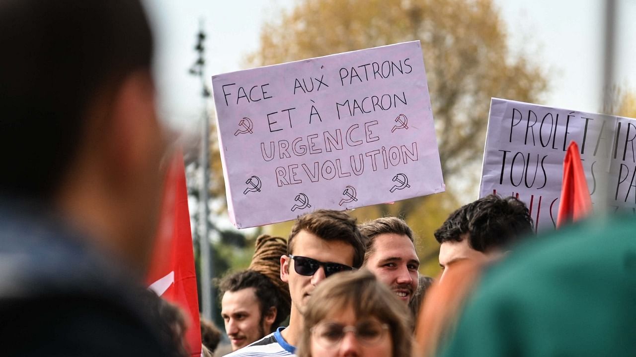 A protestor holds a placard reading "facing the bosses and Macron, urgent revolution" during a demonstration called by unions as part of the annual May Day. Credit: AFP Photo