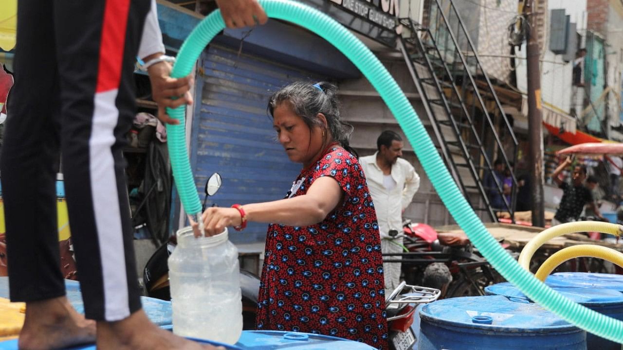 Woman fills a plastic container with drinking water on a hot summer day in New Delhi. Credit: Reuters Photo
