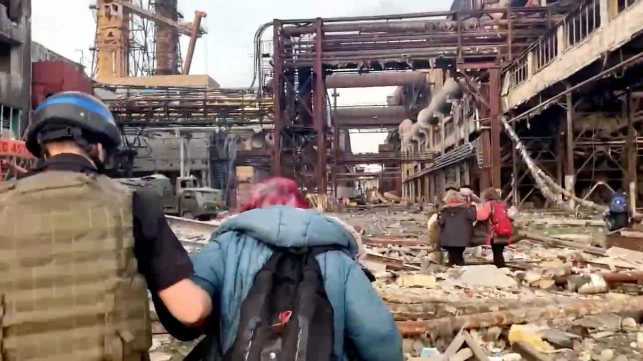 Azov regiment members walk with civilians during UN-led evacuations from the sprawling Azovstal steel plant, after nearly two months of siege warfare on the city by Russia during its invasion, in Mariupol, Ukraine in this still image from handout video released May 1, 2022. Credit: Reuters Photo