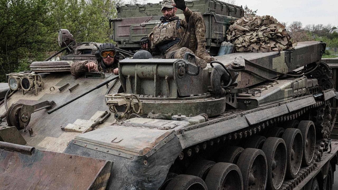 Ukrainian soldiers gestures on an armoured engineering vehicle carried on a tank transporter near Kramatorsk, eastern Ukraine. Credit: AFP Photo