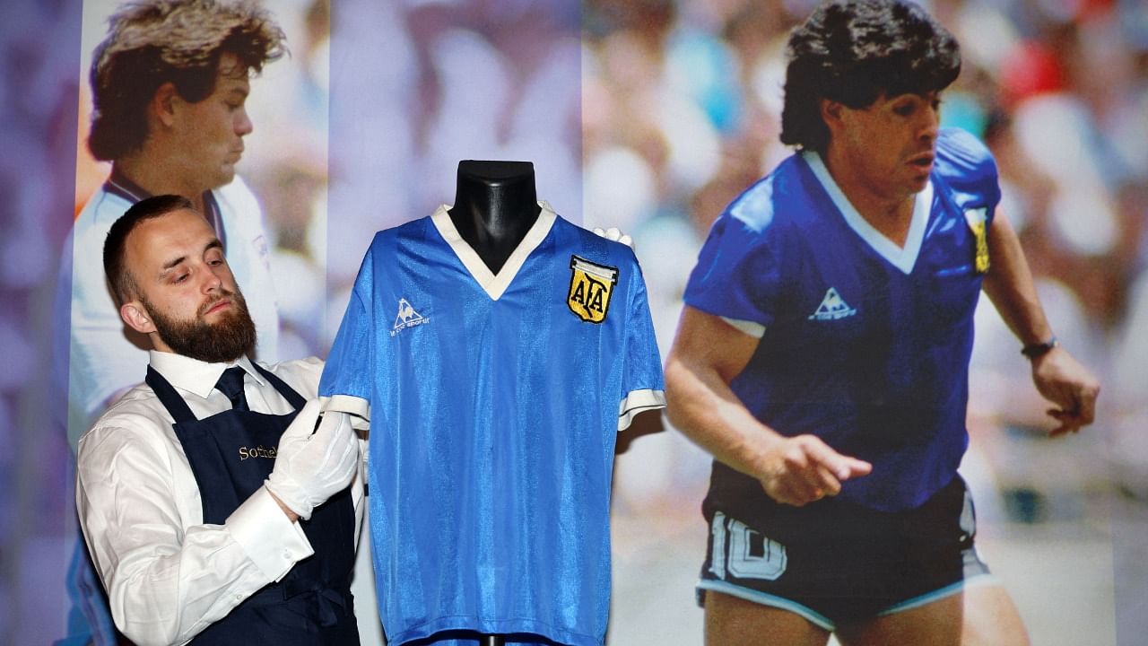 A Sotheby's technician adjusts a football shirt worn by Argentina's Diego Maradona during the 1986 World Cup quarter-final match against England. Credit: AFP Photo