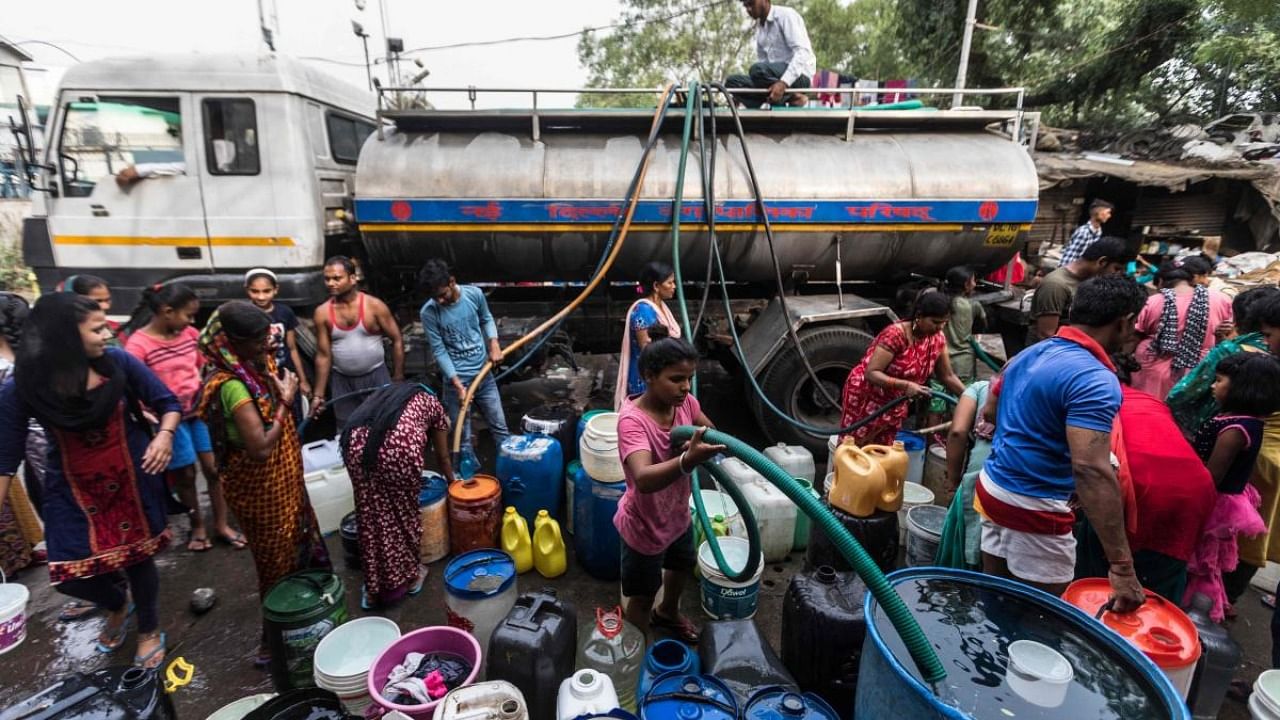 Residents use hoses to collect drinking water from a tanker truck during a hot summer day in New Delhi. Credit: AFP Photo