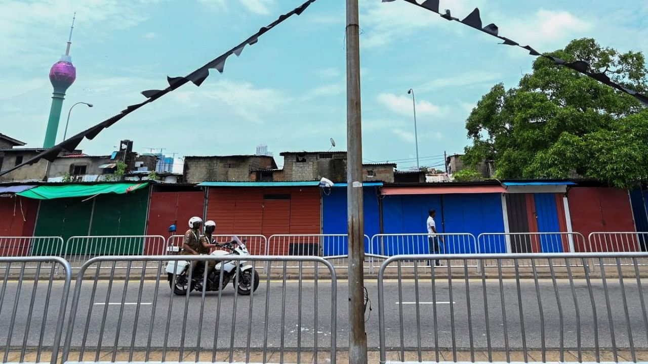 Policemen patrol on a motorbike along a street past closed shops in Colombo. Credit: AFP Photo