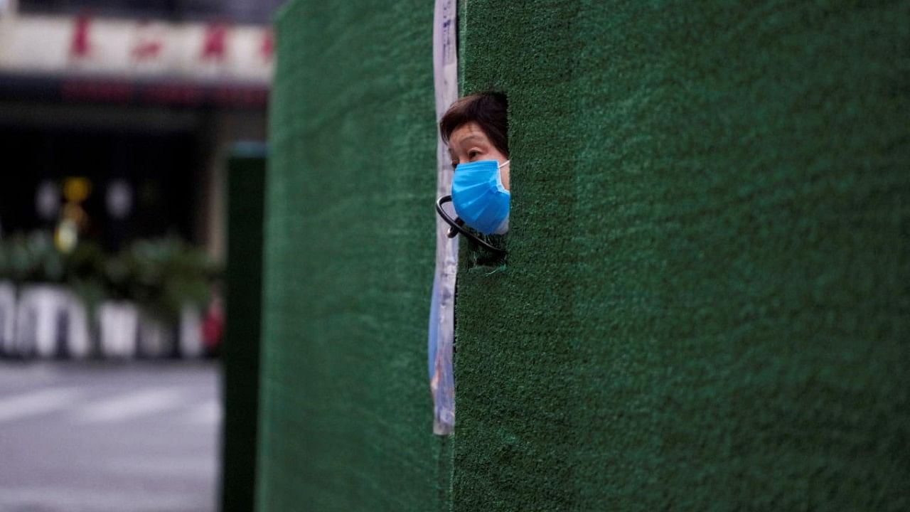 A resident looks out through a gap in the barrier at a residential area during lockdown, amid the Covid-19 pandemic, in Shanghai, China. Credit: Reuters Photo