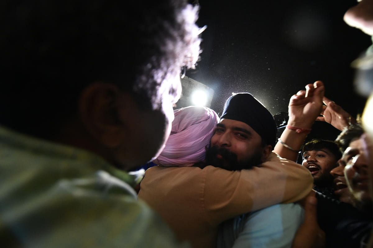 Delhi BJP spokesperson Tajinder Pal Singh Bagga greets his father upon his arrival, at his residence after being produced before the Duty Metropolitan Magistrate, in New Delhi. Credit: PTI Photo