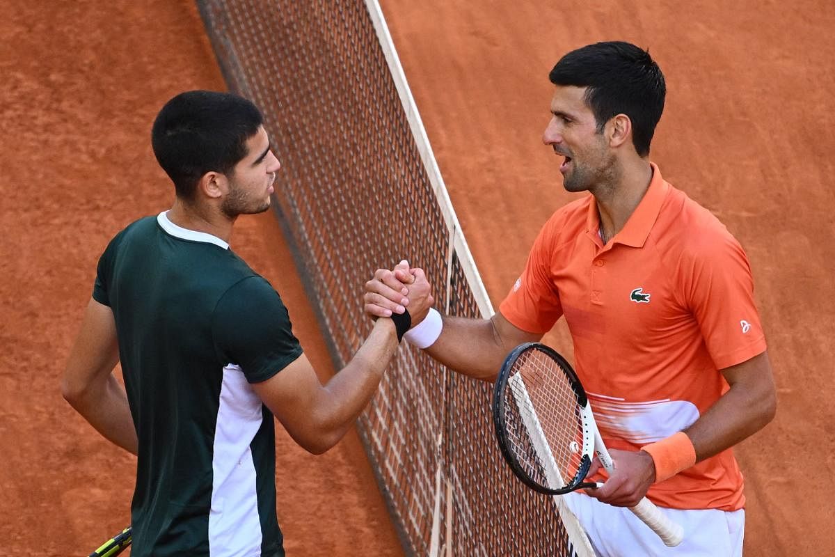 Spain's Carlos Alcaraz (L) and Serbia's Novak Djokovic shake hands at the end of their 2022 ATP Tour Madrid Open tennis tournament men's singles semi-final match at the Caja Magica in Madrid. Credit: AFP Photo