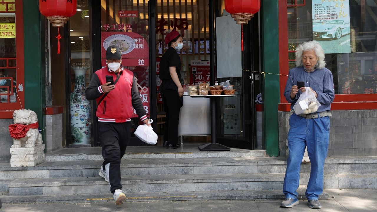 A staff member passes a bag of food to a delivery worker outside a restaurant, after the government banned restaurant dine-in services, amid the Covid-19 outbreak, in Beijing, China. Credit: Reuters File Photo