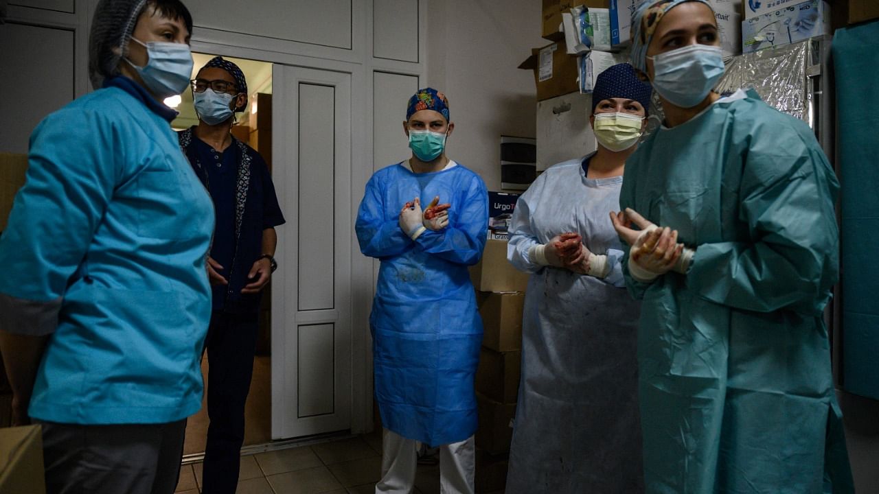 Doctors and surgeons wait outside an operating theatre during an operation on the leg of a wounded Ukrainian soldier at a military hospital in Zaporizhzhia. Credit: AFP File Photo