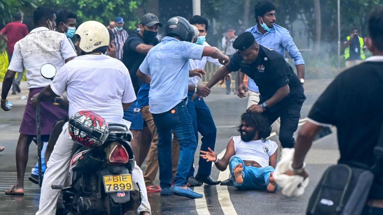 A policeman (3R) arrives at the site as demonstrators and government supporters clash outside the President's office in Colombo. Credit: AFP Photo