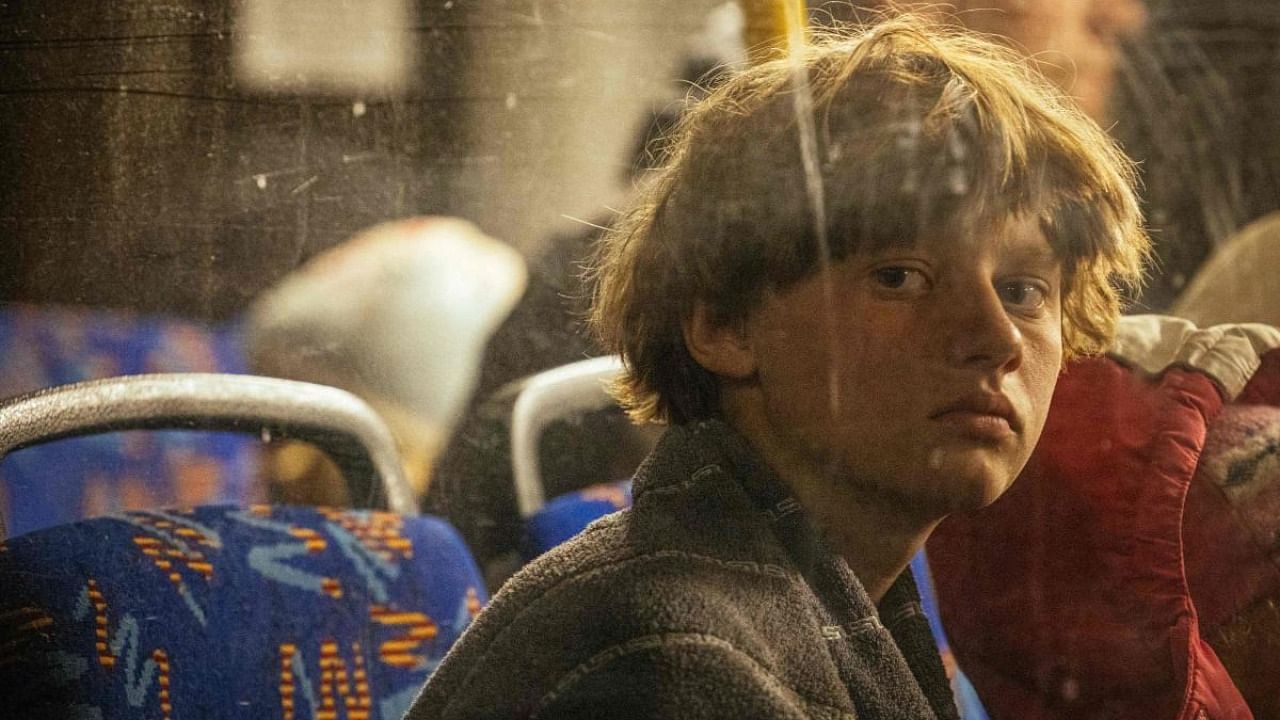 A boy looks out a bus window as people evacuated from Mariupol arrive on buses at a registration and processing area for internally displaced people in Zaporizhzhia on May 8, 2022. Credit: AFP Photo