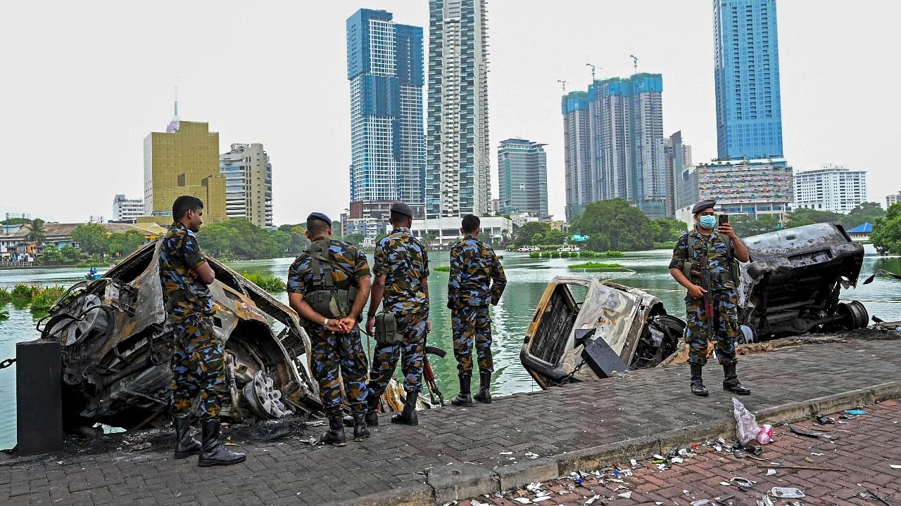 Members of Sri Lankan security personnel stand beside burnt cars near former prime minister Mahinda Rajapaksa's official residence a day after they were torched by protesters in Colombo. Credit: AFP Photo