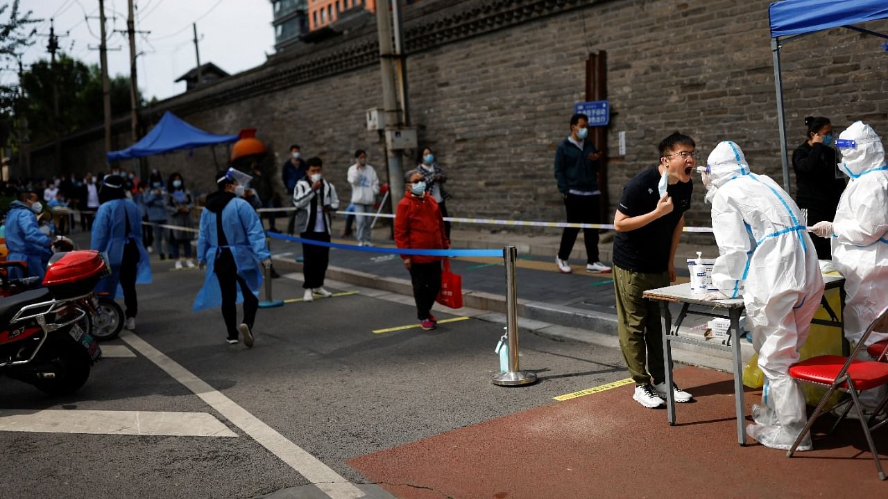 A medical worker in a protective suit collects a swab sample from a resident at a makeshift nucleic acid testing site amid the Covid-19 outbreak in Beijing, China. Credit: Reuters Photo
