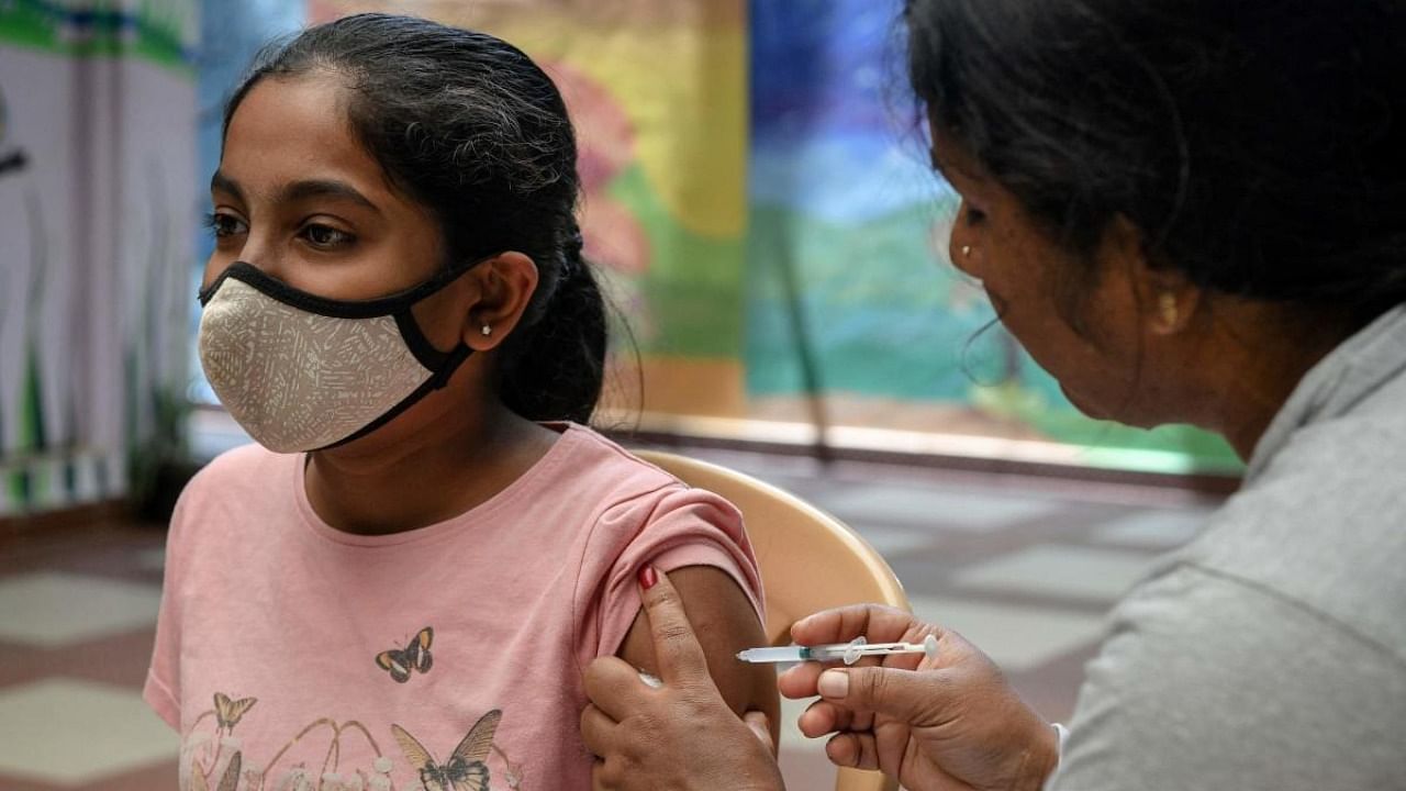 A health worker inoculates a school student with a dose of ‘Corbevax’ vaccine during a vaccination drive held for children in the age group of 12-14, as a preventive measure against Covid-19 coronavirus at a school in Bangalore on May 9, 2022. Credit: AFP Photo