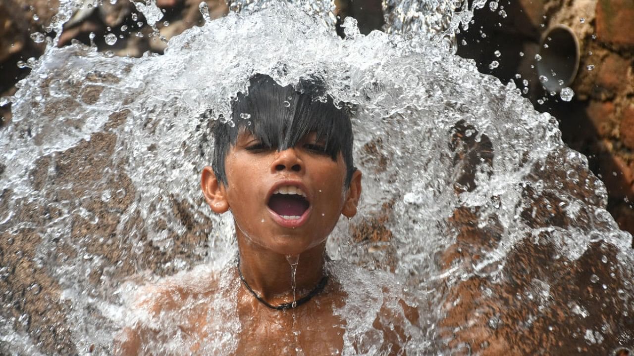 A boy takes bath under a water-pipeline on a hot summer afternoon. Credit: PTI File Photo