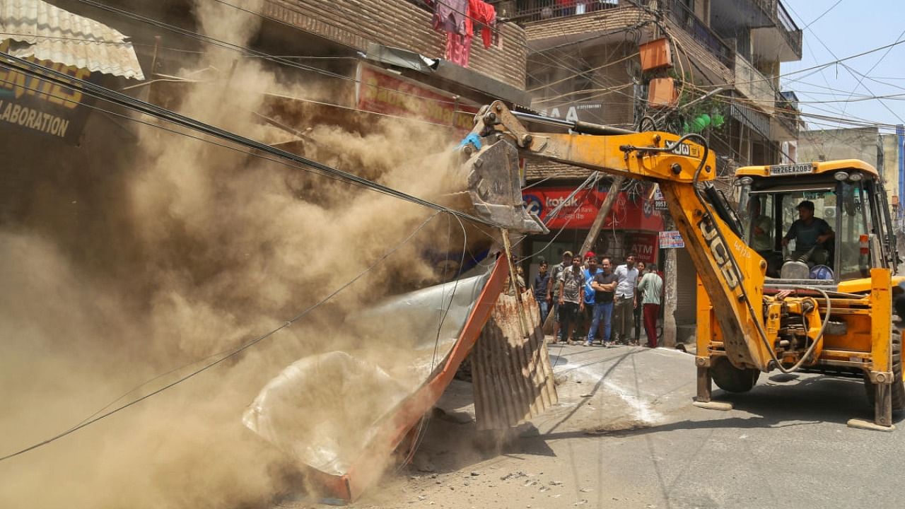 A bulldozer being used to demolish illegal structures during an anti-encroachment drive by the MCD, at Shyam Nagar in New Delhi. Credit: PTI Photo