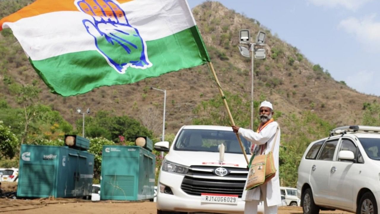 A Congress party supporter unfurls a party flag during the 'Nav Sankalp Chintan Shivir- 2022', in Udaipur. Credit: IANS Photo